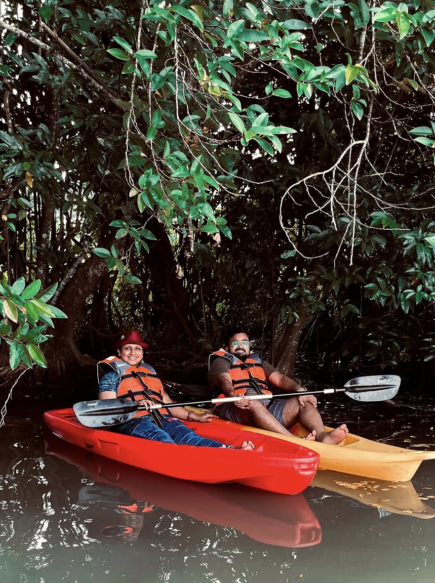 Two guests in life jackets kayaking under mangrove trees