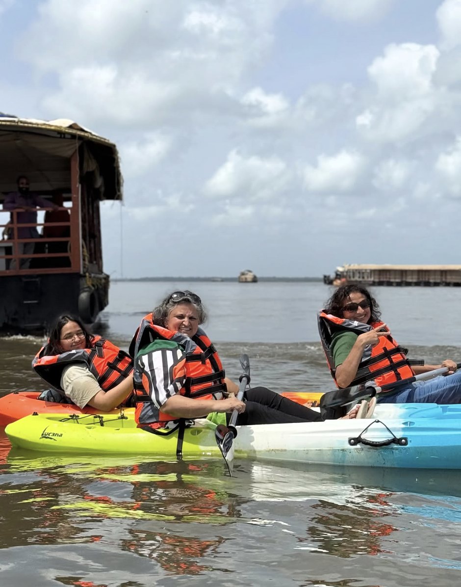Three guests in life jackets in kayaks with a houseboat behind